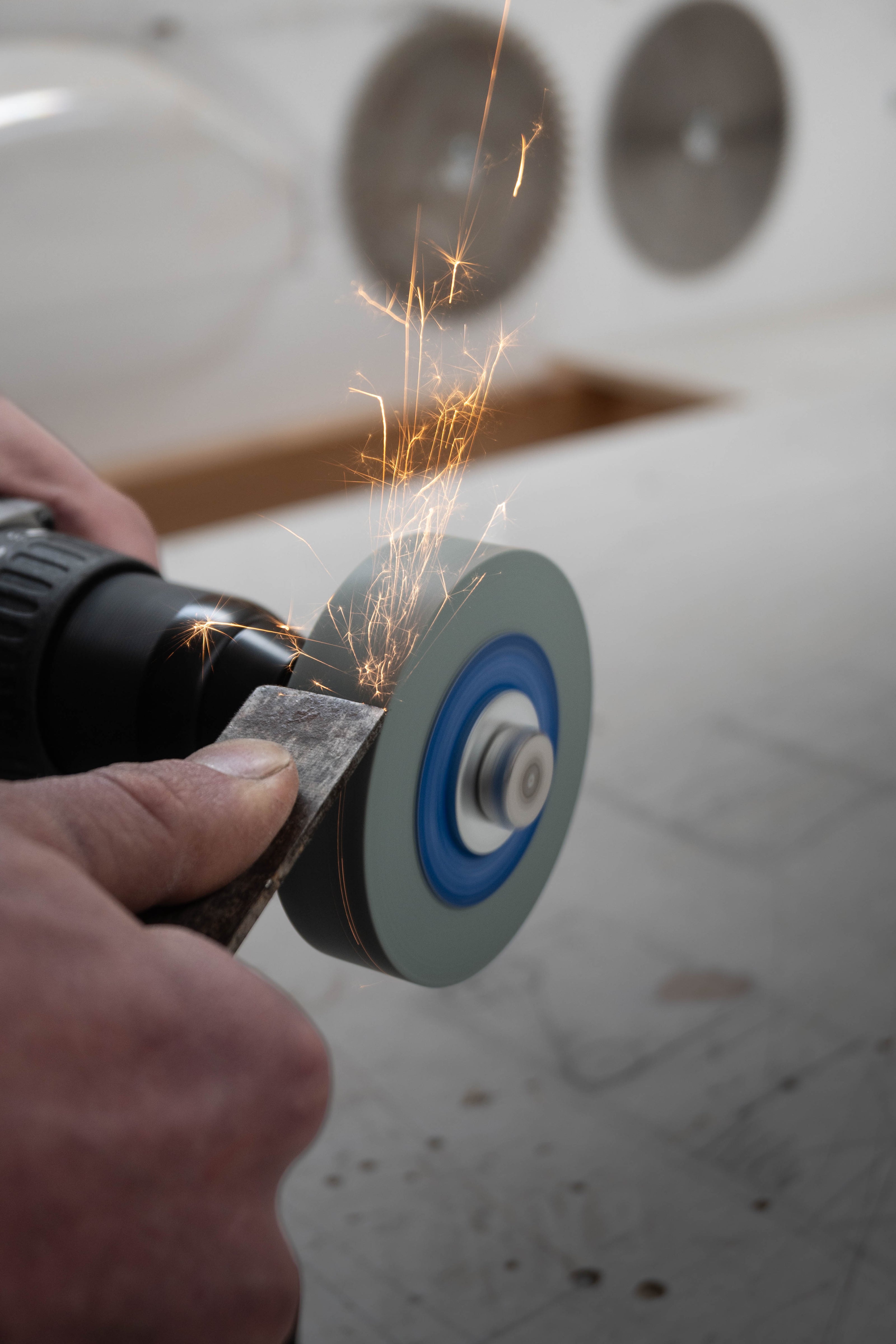 Chisel being sharpened using SharpStone 1.0 grinding disc mounted on a cordless drill, sparks flying