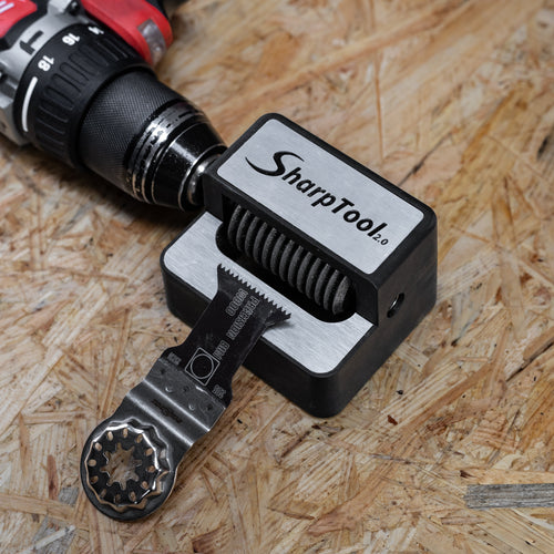 A SharpTool rotary bevel gear bit holder mounted on a cordless drill, shown on a particle board surface. The SharpTool brand is clearly visible on the black and silver holder.